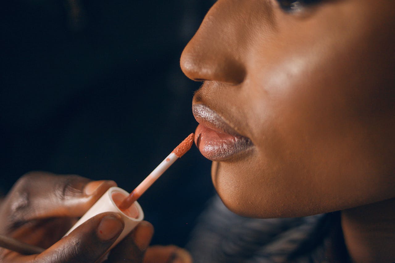 A detailed close-up of glossy lipstick being applied to a woman's lips, highlighting beauty and fashion trends.